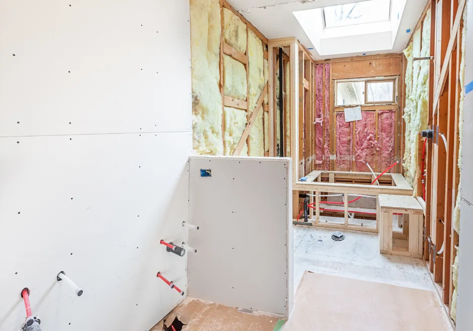 Bathroom under construction with exposed framing, insulation, and plumbing rough-in work in Los Angeles